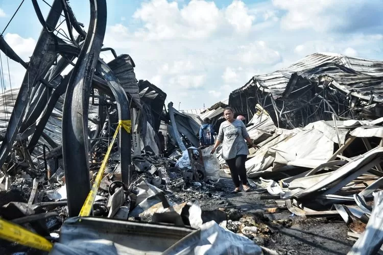 Salah seorang pedagang korban kebakaran Pasar Johar Relokasi MAJT sedang melintasi di police line.  (Ayosemarang.com/ Audrian Firhannusa)
