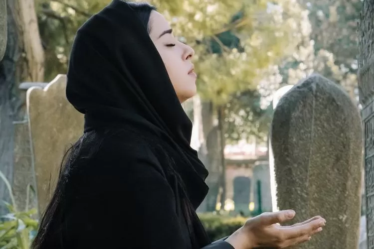 Ilustrasi foto, seorang perempuan muslim berdoa di pemakaman (pexels)