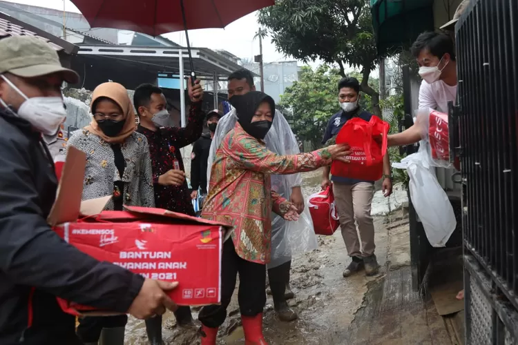 Mensos Tri Rismaharini (tengah) memberikan bantuan pada korban banjir. 