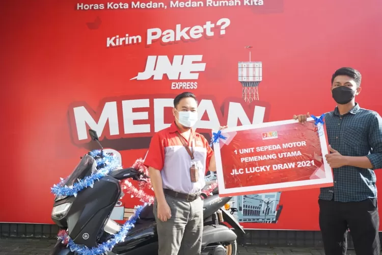 Eri Palgunadi, VP of Marketing JNE (kiri) memberikan hadiah motor NMAX kepada Wahyu Abdillah dalam Program JLC Lucky Draw 2021.  (Dok JNE)