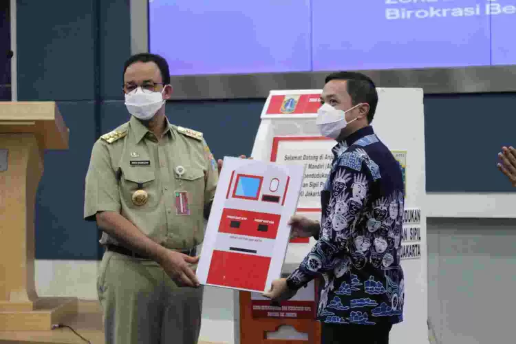 Gubernur DKI Jakarta Anies Baswedan (kiri) menerima  apresiasi  mesin ADM atas  prestasinya dalam pelayanan bidang kependudukan. 