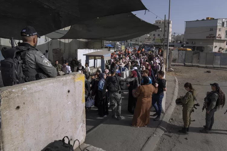 Wanita Palestina menunggu untuk menyeberangi pos pemeriksaan Qalandia dalam perjalanan mereka untuk berdoa di Masjid Al-Aqsa di Yerusalem pada hari Jumat keempat bulan suci Ramadhan antara kota Ramallah di Tepi Barat dan Yerusalem, 29 April 2022. (AP foto )