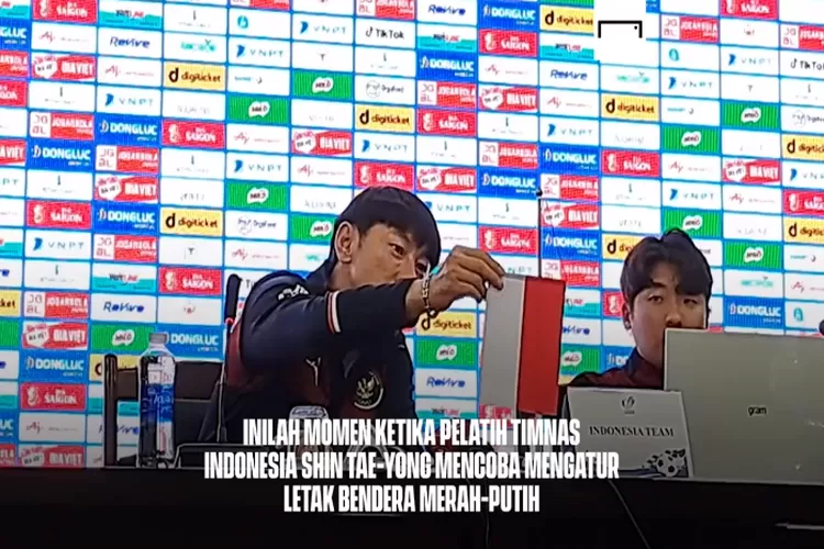 Shin Tae-Yong berusaha membetulkan posisi bendera Indonesia saat jumpa pers SEA Games 2021 (angkapan layar unggahan akun twitter @GOAL_ID)