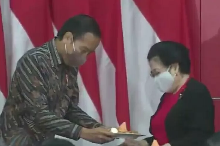 Jokowi menyerahkan potongan tumpeng HUT-nya yang ke-61 kepada Ketum PDIP Megawati Soekarnoputri. (Tangkapan layar YouTube.)