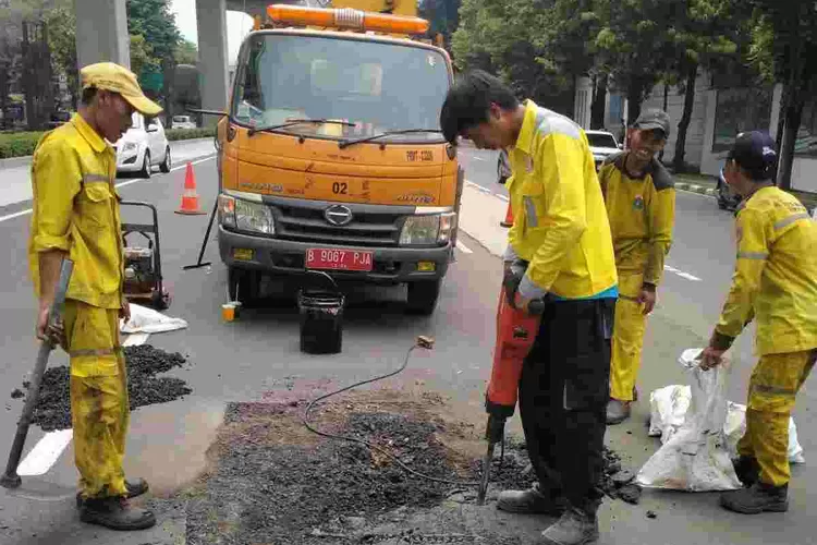 Petugas dari Dinas Bina Marga melakukan pekerjaan  memperbaiki jalan rusak akibat pekerjaan proyek LRT Jabodegabek.