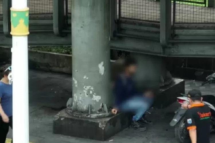 Seorang pria membuang sampah sembarangan di bawah JPO GBK, Jaksel.