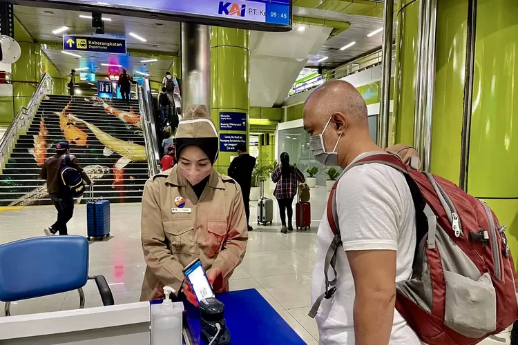 Petugas dengan menggunakan kostum Pahlawan tengah melayai calon penumpang di Stasiun Gambir