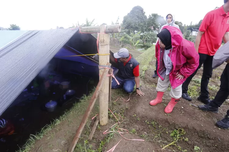Mensos Tri Rismaharini (membungkuk) menjenguk warga di tenda pengugsian gempa Cianjur. 