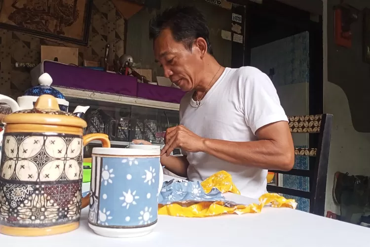 FOKUS: Suyono sedang fokus menempelkan kain perca ke media gelas untuk dijadikan kerajinan batik rekat di Say Galeri Kelurahan Sukmajaya, Kota Depok, Selasa (15/1). ASHLEY KAESANG/RADAR DEPOK 