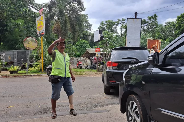 Ujang saat membantu mengatur lalu lintas. 