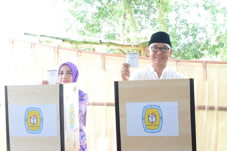 Plt Bupati Bogor Iwan Setiawan dan istri menggunakan hak pilihnya di Pilkades Leuwimalang, Kecamatan Cisarua, Minggu 12 Maret 2023. (Diskominfo Kabupaten Bogor)