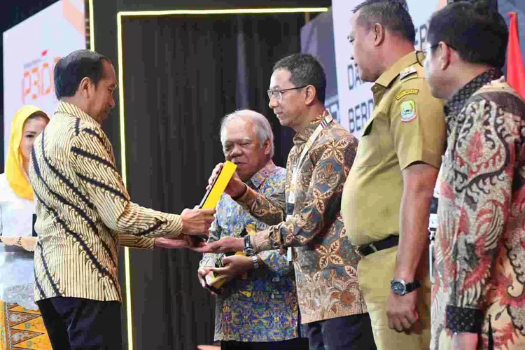 Presiden Joko Widodo menyerahkan penghargaan kepada Pj Gubernur DKI Jakarta Heru Budi Hartono  atas komitmen Pemprov DKI peduli pada produk lokal.