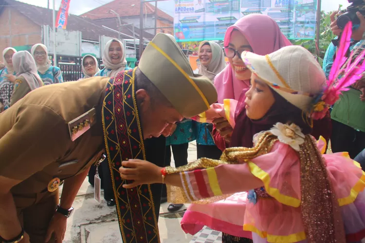 Bupati Kudus Hartopo disambut gadis kecil dan mendapat kalungan slayer panjang, saat hadir untuk membuka penilaian lomba desa di Desa Padurenan Kecamatan Gebog, Senin 27 Maret 2023. (Foto: Disinfokom Kudus)