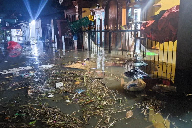 Salah satu korban terdampak banjir membersihkan material sampah yang terbawa banjir ke dalam rumahnya di Anak Air Bukittinggi (Harianhaluan.com/Vesco)
