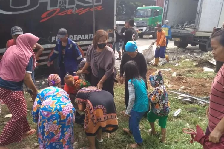 Ibu-Ibu berkumpul mengambil ikan yang berceceran setelah kecelakaan truk ikan di Tol Jakarta-Cikampek