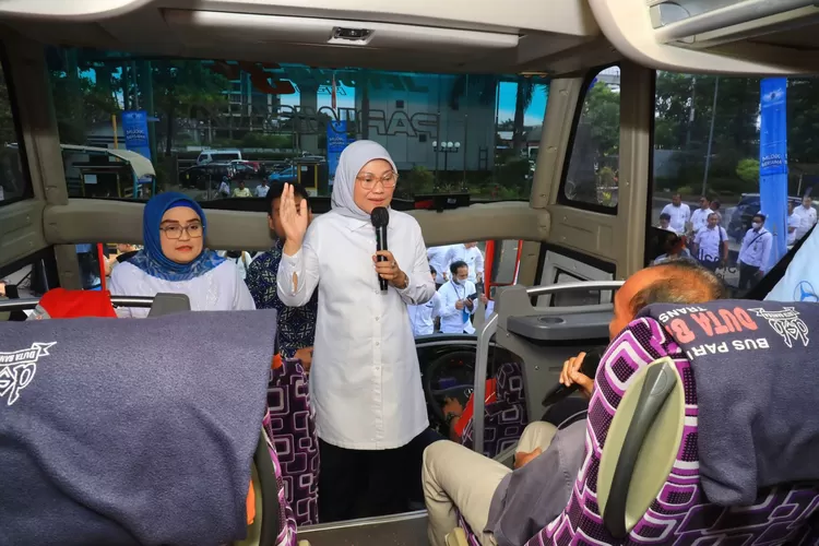 Menaker Ida Fauziyah masuk ke dalam bus berdialog dengan pekerja yang akan mudik. 
