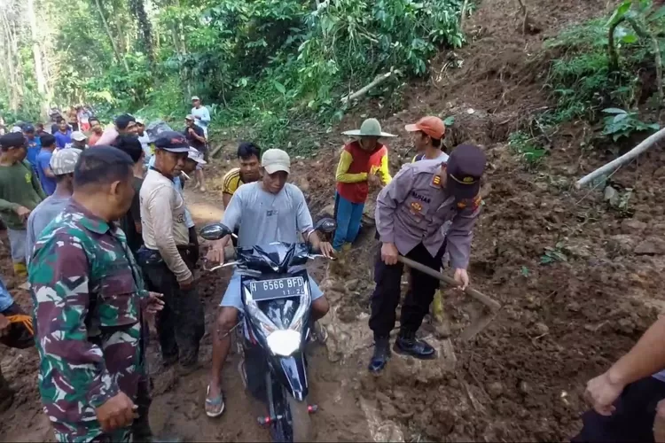 Warga, TNI dan Polri bergotong royong menggunakan alat manual menyingkirkan material tanah akibat tebing longsor yang menutup jalan. (edi prayitno/kontributor Kendal)