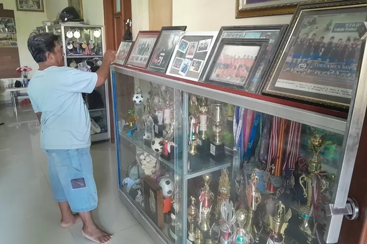 Paman Ernando Ari Sutaryadi, kiper Timnas Indonesia, saat merapikan foto-foto dan medali keponakannya. Keluarga besar Ernando Ari akan nobar untuk mengungkapkan dukungan.  (Ayosemarang.com/ Audrian Firhannusa)