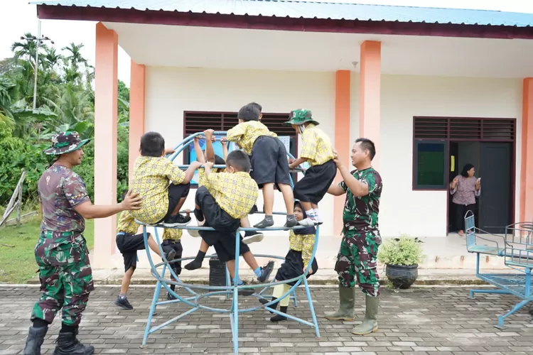 Personel Satgas TMMD manfaatkan waktu istirahat bermaindengan anak-amak. 