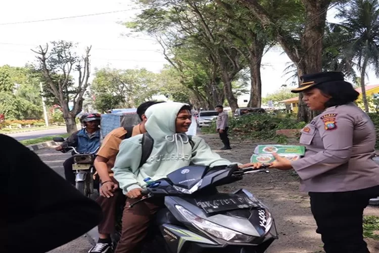 Seorang Polwan Polres Langkat sedang membagikan Nasi kotak kepada warga pengendara Sepeda Motor saat melintas Mako Polres Langkat (Realitasonline.id/AA)