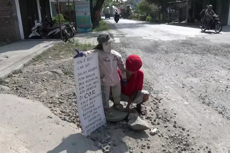 Irfak saat memasang patung anak kecil wajg sang cucu sebagai bentuk protes jalan rusak di Desa Ngemplak Mranggen.  (Istimewa)