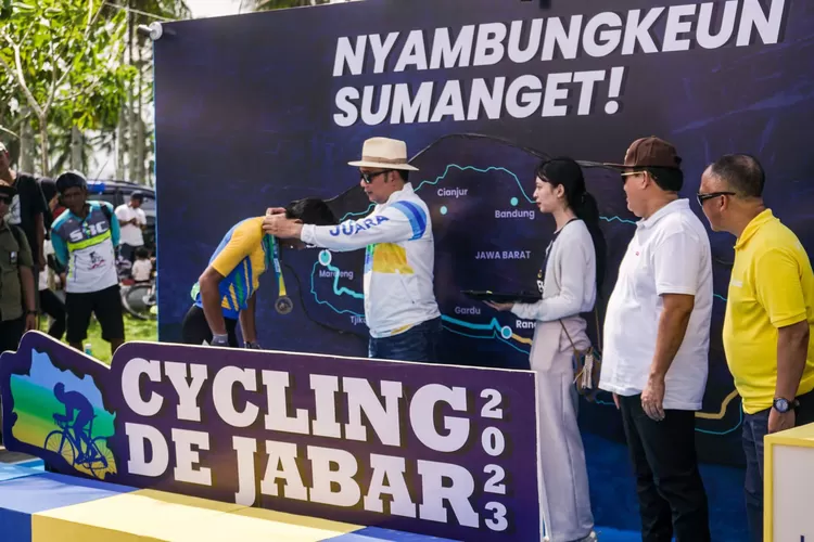 Gubernur Jawa Barat Ridwan Kamil mengalungkan medali kepada seorang peserta Cycling de Jabar 2023. (bjb)