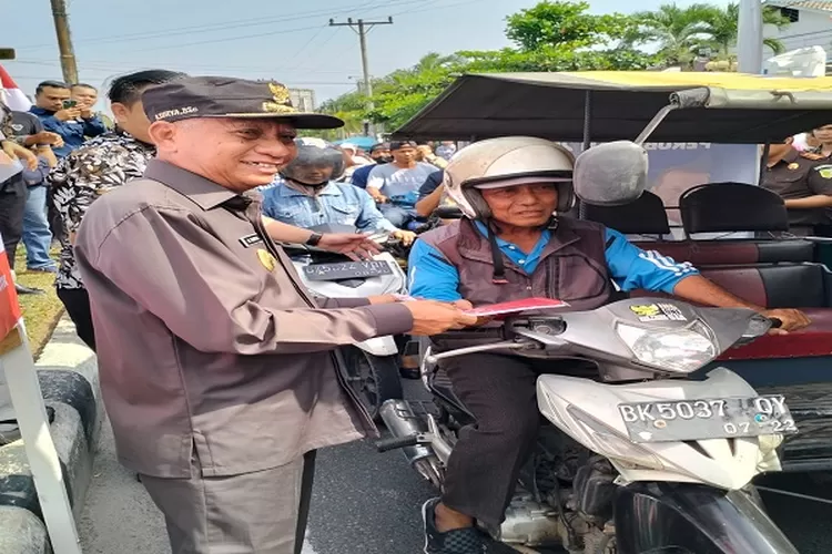 Bupati Asahan Surya saat membagian bendera kepada masyarakat yang melintas di Jalan Cokroaminoto Kisaran&nbsp; (Realitasonline.id/HS)