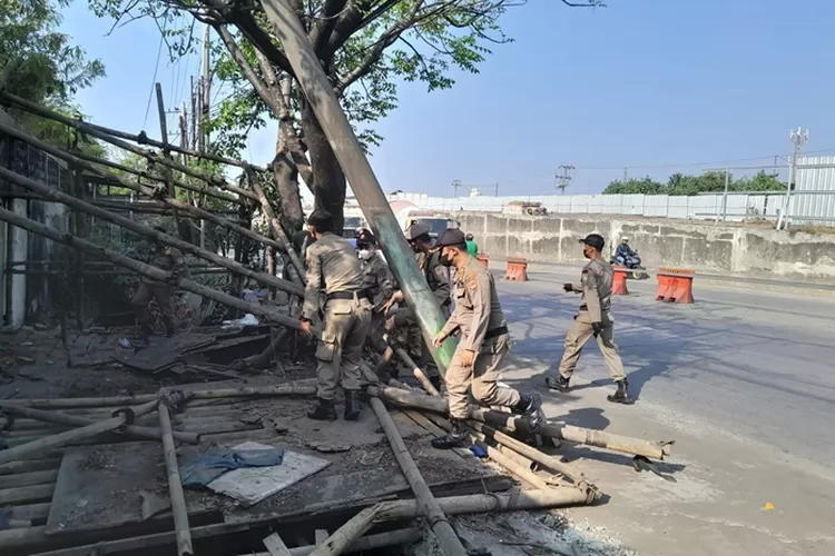 Satpol PP membersihkan kios-kios liar di Jalan Pantura Semarang untuk memperlancar pembangunan Proyek Jembatan Tol Kaligawe.  (Ayosemarang.com/ Audrian Firhannusa)