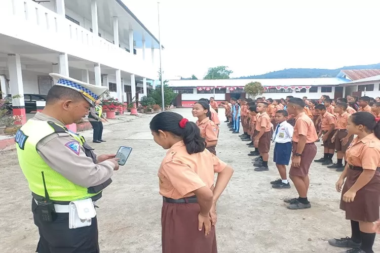 KBO Lantas Iptu Harapan Sihombing memberi panduan menggunakan aplikasi ke salah satu siswi di Taput  (Realitasonline.id/Dok)