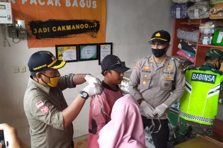 Camat Bayung Lencir, M Imron SSos MSi, didampingi Polsek Bayung Lencir AKP Jon Roni Hasibuan, saat memasangkan masker kepada salah satu warga, yang tidak memakai masker, saat dilaksanakannya razia masker di jalan lintas Palembang-Jambi, Jumat (24/7).