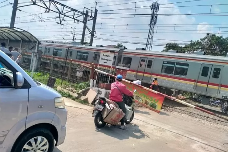 PERLINTASAN RAWAGENI: Seorang pengendara motor melintas pintu perlintasan kereta api Rawageni Kota Depok yang dijaga warga setempat usai dibuka secara paksa masyarakat, Rabu (22/6). FOTO: ARNET KELMANUTU/RADAR DEPOK