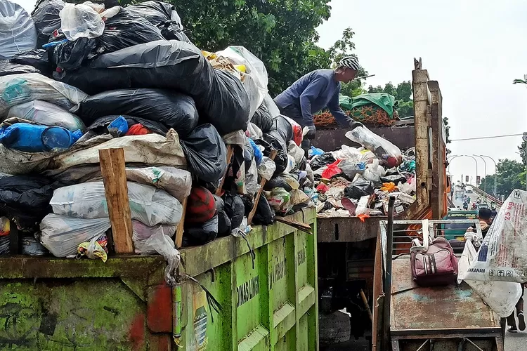 Petugas menaikan sampah kedalam truk sampah di Jalan Raya Perbatasan Kota Bandung dan Cimahi, Kota Bandung, Selasa (30/11). (FOTO: TAOFIK ACHMAD HIDAYAT/RADAR BANDUNG)