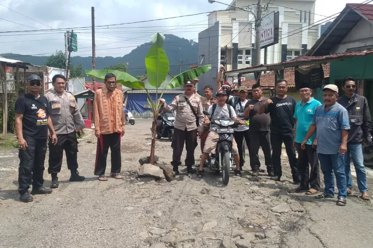 Petugas kepolisian mengawal warga yang melakukan aksi protes jalan rusak dan berlubang dengan menanam pohon pisang di Jalan Raya Tambakmekar Subang, Selasa (13/9/2022). (ist)