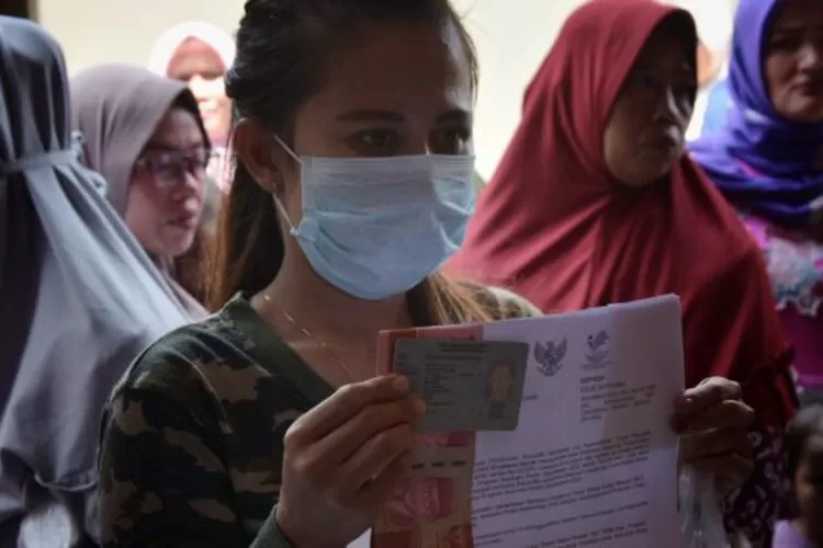 Warga penerima BLT BBM mengenakan kalung emas berpose untuk didokumentasikan petugas PT Pos Indonesia di Desa Sukadanau Kecamatan Cikarang Barat Kabupaten Bekasi, Kamis (15/9/2022). ARIESANT/RADAR BEKASI 