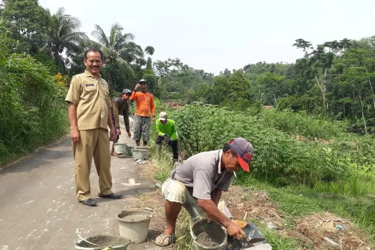 TINJAU: Sekdes Karehkel, Kecamatan Leuwiliang, Kabupaten Bogor, Suhandi, saat meninjau kekompakan warga membangun drainase jalan desa, belum lama ini.