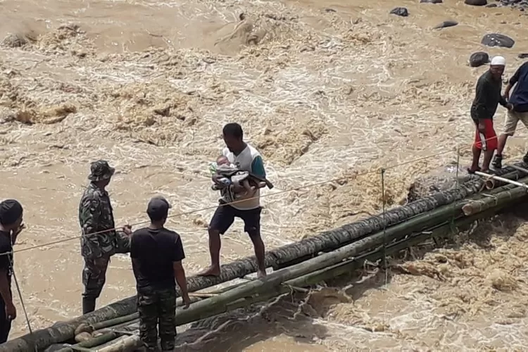 DIEVAKUASI: Warga mengevakuasi bayi ke luar kampung yang terdam-pak longsor melewati jembatan darurat yang terbuat dari bambu dan pohon kelapa. 