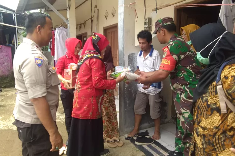 PEDULI:Babinsa Pelda Lumban Gaol bersama Bhabi-nkamtibmas Aipda Heru Budiyanto memberi  sembako  kepada warga Kelurahan Karade-nan, Kecamatan Cibinong, yang kurang mampu.