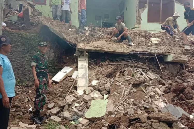 EVAKUASI: Anggota TNI bersama warga membersihkan longsoran rumah di Kecamatan Megamendung.