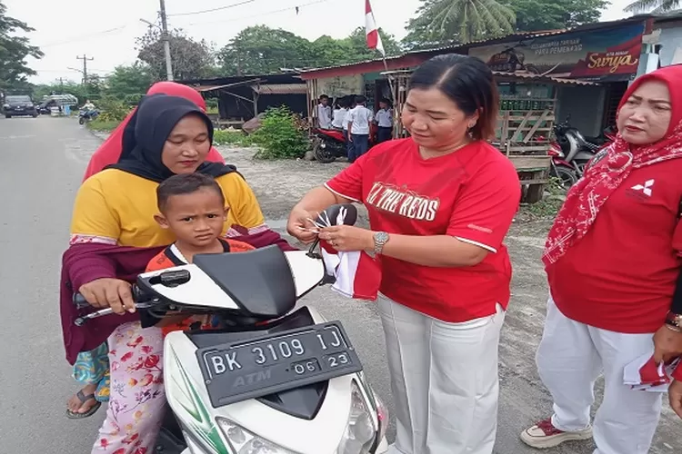 Petugas Puskesmas Pantai Labu saat memasangkan bendera Merah Putih di sepeda motor warga yang melintas di depan puskesmas (Realitasonline.id/zul)