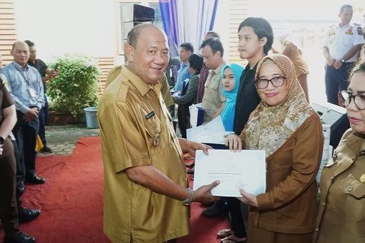 Plt Bupati Langkat Syah Afandin saat menyerahkan penghargaan  atas prestasi pencapaian target PAD tahun 2022 kepada Kepala  Badan Pendapatan Asli Daerah Kabupaten Langkat  (Realitasonline.id/Nanda)