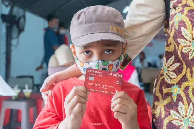 Seorang anak memperlihatkan Kartu Anak Jakarta  yang  akan menerima bantuan sosial  setiap  tiga bulan sekali.