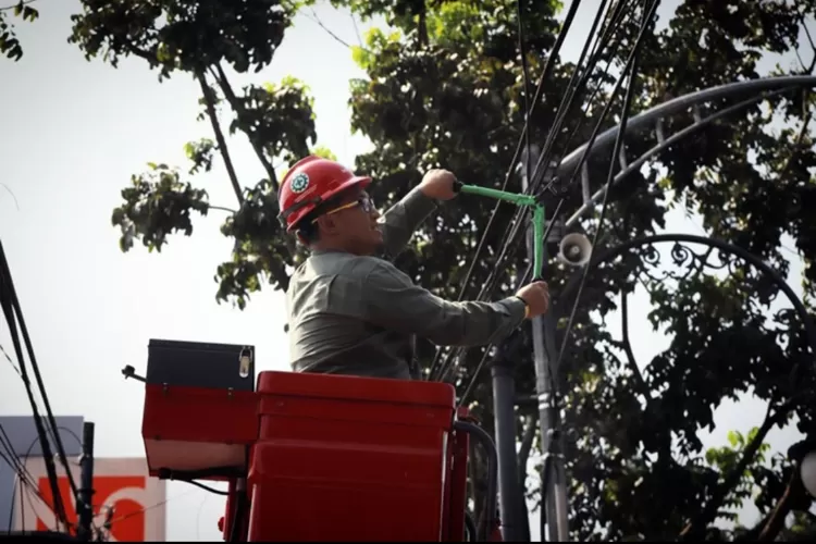 Ketua Komisi A DPRD Kota Bandung H. Rizal Khairul, S.IP., M.Si., memotong kabel untuk memulai proses penurunan kabel FO, di Jalan L.L.R.E. Martadinata, Bandung, kemarin ini. Ariel/Humpro DPRD Kota Bandung.