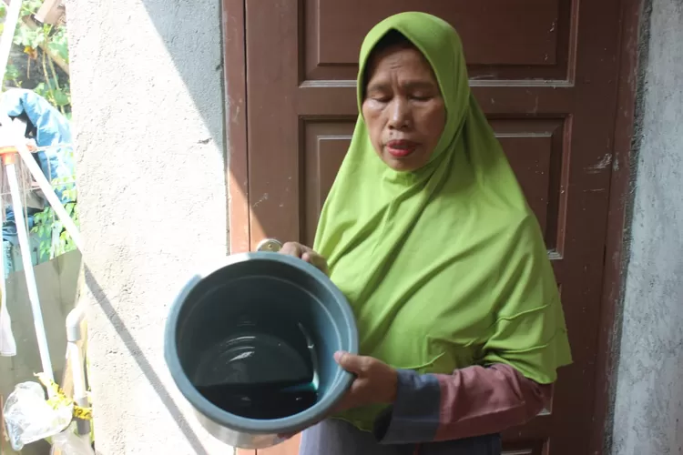 Sumiati memperlihatkan air sumur miliknya yang diduga tercemar BBM