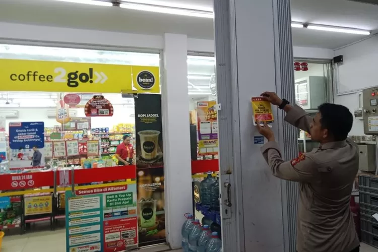 Kapolsek Mampang Kompol David Yunior Kanitero memasang stiker nomor aduan di minimarket untuk mengantisipasi kerawanan kejahatan seperti perampokan.  (Foto: dok. Istimewa)