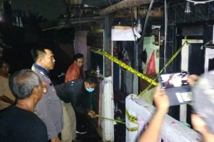 PASANG : Aparat kepolisian saat memasang garis polisi pasca pemadaman api di Jalan Dadap Dalam II, RT 7/1, Kelurahan Mekarjaya, Kecamatan Sukmajaya, Kamis, (24/8). (EJAR RAMADHAN/RADAR DEPOK)