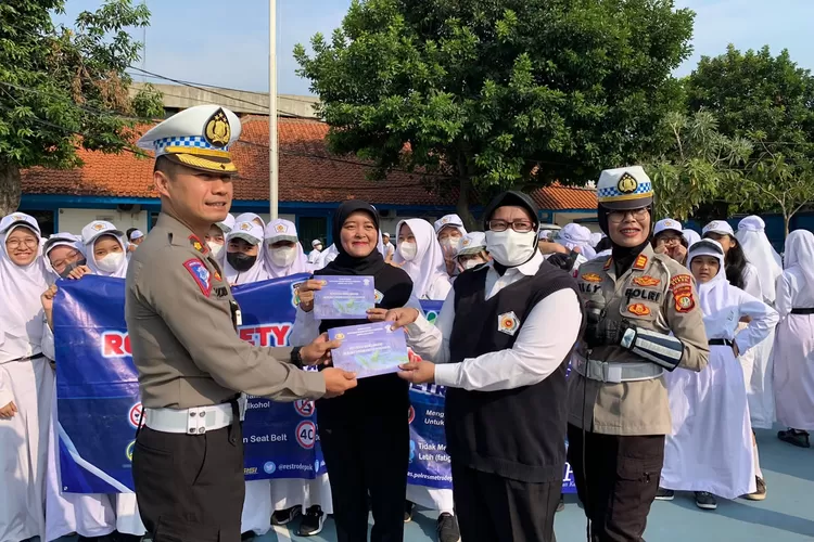 Kasat Lantas Polres Metro Depok, Kompol Multazam Lisendra, menyerahkan buku  Road Safety Partnership Action usai menjadi inspektur upacara, di SMP/SMA Bintara, Senin (4/9). (Satuan Lalu Lintas Polres Metro Depok)