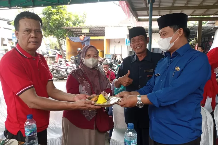 TASYKURAN : Kepala UPT Pasar Sukatani Hidayat (kanan) menyerahkan potongan nasi kuning tumpeng kepada ketua paguyuban pedagang pasar Sukatani (P3S), Entis Sutisna di acara tasyakuran HUT ke 32 Pasar Sukatani. ANDIKA EKA/RADAR DEPOK