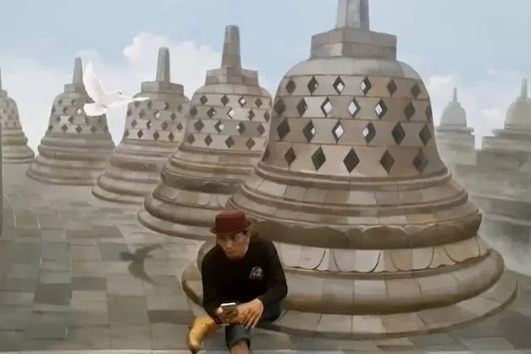 SENIMAN : Sulis Listanto foto di depan lukisan sebuah candi. ANDIKA EKA/RADAR DEPOK