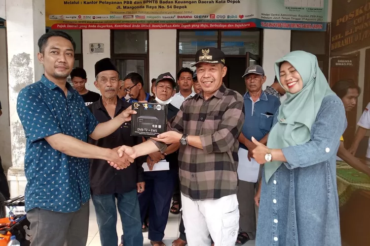 PENERIMAAN : Disaksikan Kasie Kemas Kelurahan Boponter, Eli Elyawati dan pengurus RT/RW,  secara simbolis Lurah Boponter, Agus Suryana menerima bantuan gratis 1.384 Unit STB TV Digital dari vendor Kemenkominfo RI untuk warga miskin Boponter. ANDIKA EKA/RADAR DEPOK