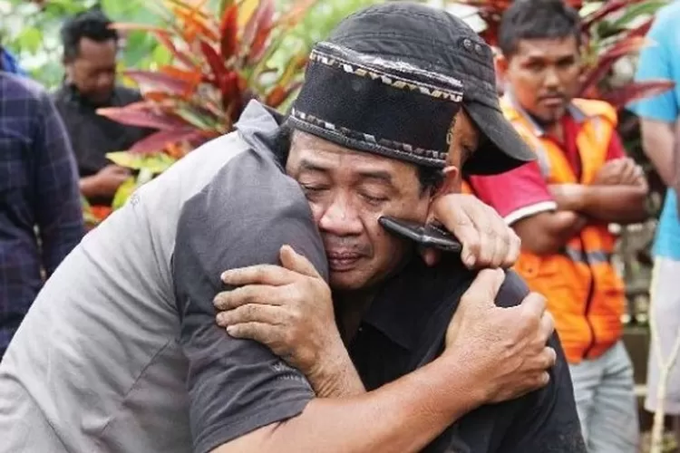 fin (kanan) ayah mendiang Farzah dipeluk pelayat saat pemakaman di TPU Sudimoro, Kota Malang (24/10). (Darmono/Jawa Pos Radar Malang)